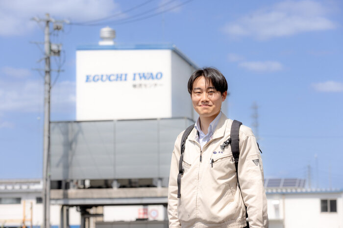 倉庫前に立つ作業着姿のモビリティ第1営業部K.Tさん