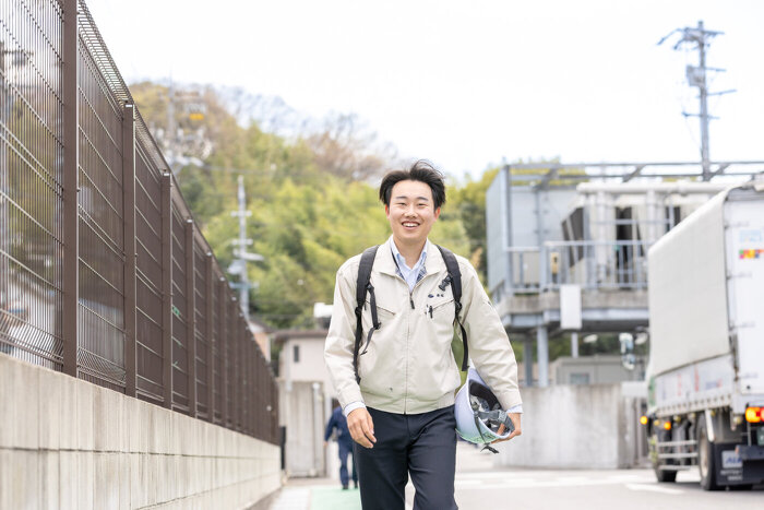 ヘルメットを抱えて倉庫へと向かって歩くモビリティ第1営業部K.Tさん